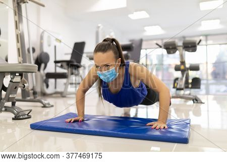 Woman have indoor training with push-ups in gim with medical facemask. Female breathes deeply stock photo