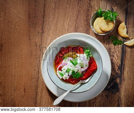 Roasted Yellow And Red Bell Pepper Salad With Capers And Olives In A Blue Bowl On A White Background