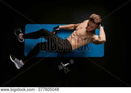 Muscular Caucasian Man Training Abs On Floor In Sports Club. From Above View Of Handsome Young Sport