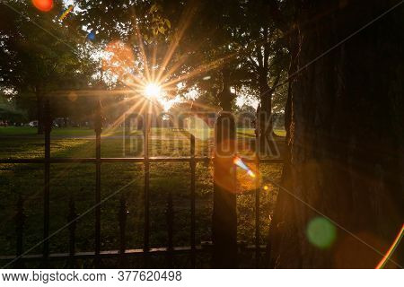 Long Shadows Through Wrought Iron Fence Surrounding La Fayette Park With Lens Flare Aged Photo Effec