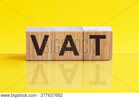 Vat On Wooden Cubes Over Blur Background With Copy Spcae, Financial Concept Background. Yellow Backg