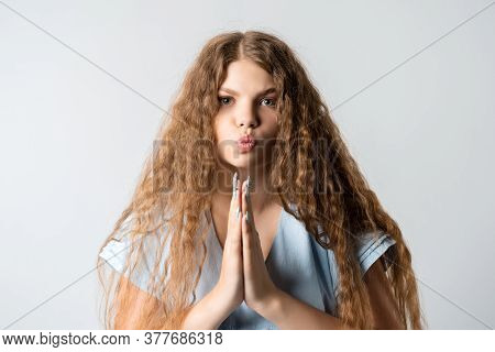 Please, Help Me. Emotive Pleased European Girl With Curly Long Hair, Keeps Hands In Praying Gesture,