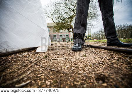 Bride And Groom Wedding Couple Feet With Weddingdress And Suit On A Country Road. High Quality Photo