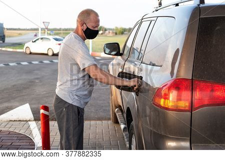 Man In A Black Protective Mask Refills An Suv Car At A Gas Station, Virus Protection