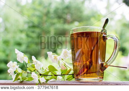 Green Tea Cup With Teaspoon And Floweer Buds, With Copy Space. Summer Menu Concept.