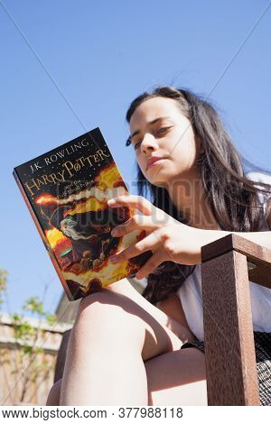 A Photograph Of A Child Reading Harry Potter And The Half Blood Prince Against A Blue Sky, Taken 21s