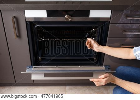 The Girl Opens The Built-in Oven Door And Takes Out A Baking Sheet. Built-in Oven With Display In A 
