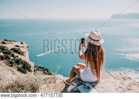 Digital Nomad, Woman In The Hat, A Business Woman With A Laptop Sits On The Rocks By The Sea During 