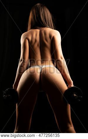 Sexy Fit Woman Works Out With Dumbbells On Black Dark Background. Athletic Young Woman Doing A Fitne