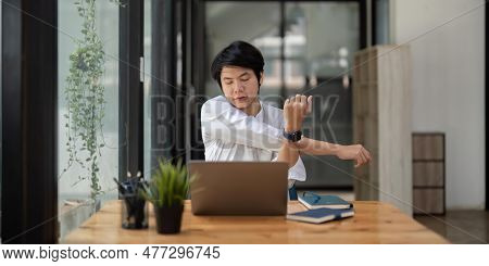 Stretching Oneself Asian Business Man With Laptop In Cafe. Tried From Work, Stretch Oneself