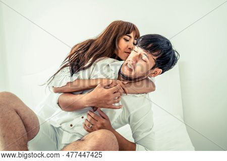 Playful Young Couple Teasing In Home Bedroom In The Morning.