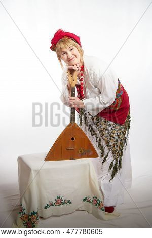Cheerful Funny Adult Mature Woman Solokha With Musical Balalaika. Female Model In Clothes Of Nationa