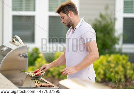 Man At A Barbecue Grill. Male Cook Preparing Barbecue Outdoors. Bbq Meat, Grill For Picnic. Roasted 