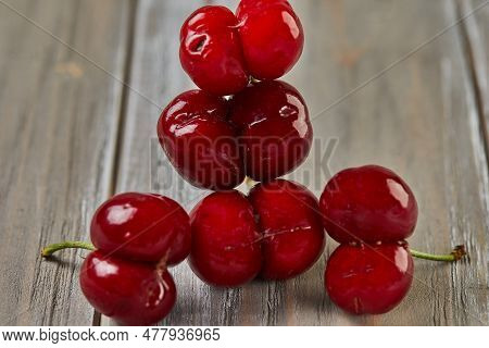 Natures Oddity: Ugly, Irregularly Shaped Cherry Stands Out Against A Rustic Wooden Backdrop