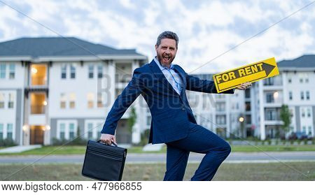 Rent House With Smiling Renter Adviser Man Outdoor. Renter Adviser Man With For Rent Sign. Rent Prop