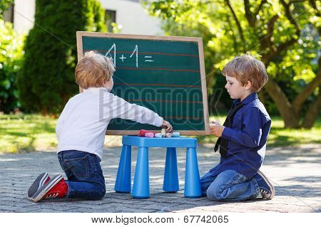 Two Siblinig Boys At Blackboard Practicing Mathematics