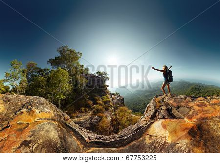 Hiker standing on top of the mountain with raised hand