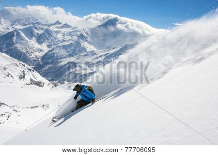 Skier in high mountains during sunny day.Freeride in fresh powder snow