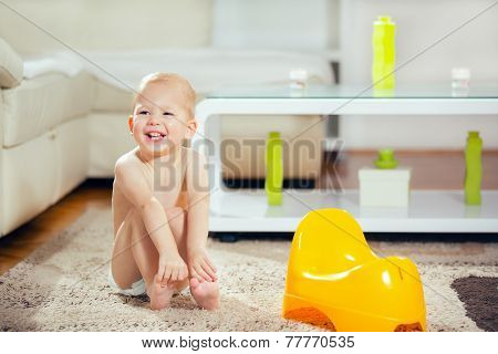 Little baby boy sitting next yellow potty