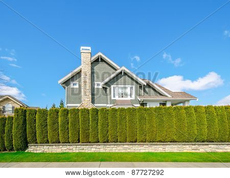 Beautiful house behind green hedge fence. Landscape trimming design. House exterior.
