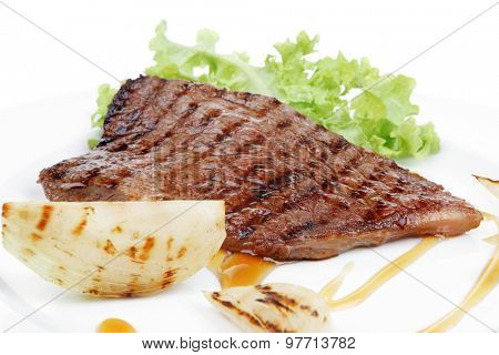meat food : grilled steak on green lettuce salad , with roast onion, on dish isolated over white background