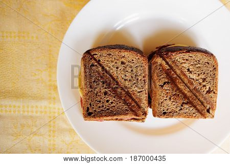 toasted ham and cheese sandwich on a white circular plate