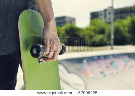closeup of a young caucasian man with a skate board in his hand in an outdoors skate park
