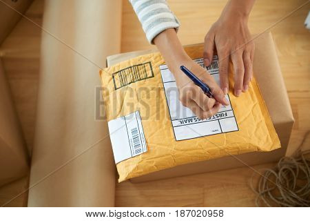 Hands of woman writing address on first class mail package