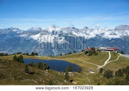Ski facilities beside lake on top of the hill with the Alps in background in Nendaz, Switzerland.