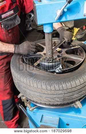 Man in Car repair levers a used tyre of the rim