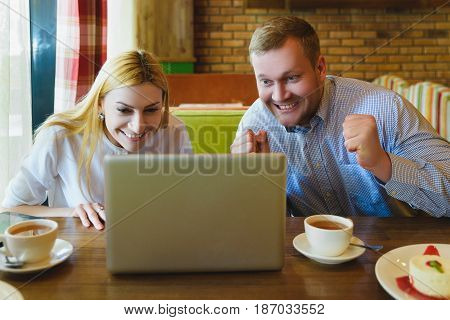 Business meeting in a cafe. Man and woman Looking at the laptop. They are happy and successful.