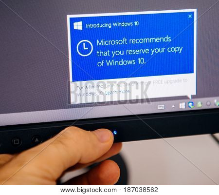 PARIS FRANCE - AUG 5 2015: Introducing Windows 10 - Man touching display with message in the dashboard Microsoft recommends to reserve the copy of Windows 10 during the free upgrade period