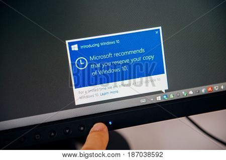 PARIS FRANCE - AUG 5 2015: Introducing Windows 10 - Man touching display with message in the dashboard Microsoft recommends to reserve the copy of Windows 10 during the free upgrade period