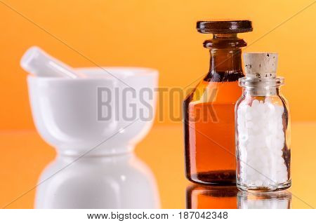 medical glass bottles with mortarorange backgroundselected focus narrow depth of field