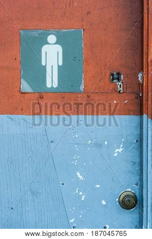Men's bathroom sign in an old abandoned gas station with cracked paint.