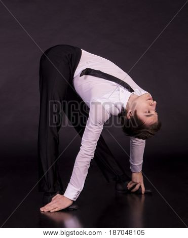 Extraordinary gymnast on a black background. The man with no bones. Studio photography of circus performers.