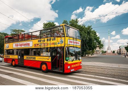 Riga, Latvia - July 2, 2016: Touristic Bus For Sightseeing In Kalku Street With View Of Freedom Monument On Background.  City Sightseeing Tour.