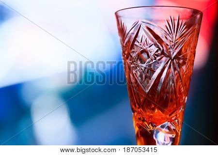 Crystal glass on a high leg for vodka on blurred light background closeup