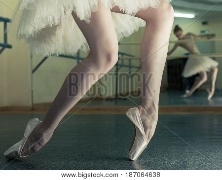 Ballerina in pointe shoes and a pack stands on the fingers of the machine. Reflection in the mirror in the ballet class. Classical ballet. Prima ballerina. Shooting close-up.