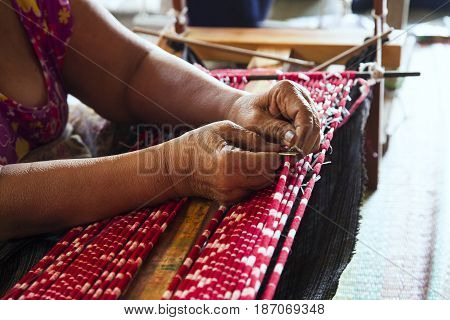 Old asia women demonstrate to procedure of making Thai Silk weaving in small weaving mill