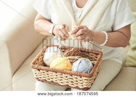 Hands of woman knitting a scarf at home