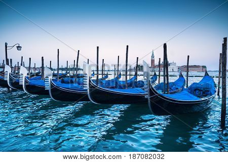 Venice gondolas or gondole on a blue sunset twilight and San Giorgio Maggiore church landmark on background. Italy Europe.