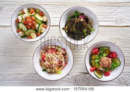 four salad mix bowls healthy food on white wood table