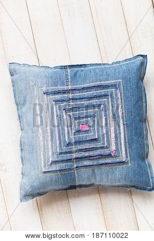 textile blue pillow on white background, closeup on decorated product with stitching and designer decor in the form of labyrinth cut in fabric through which visible colored lining, top view, vertical