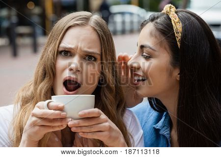 Cheerful friends srinking coffee at sidewalk cafe in city