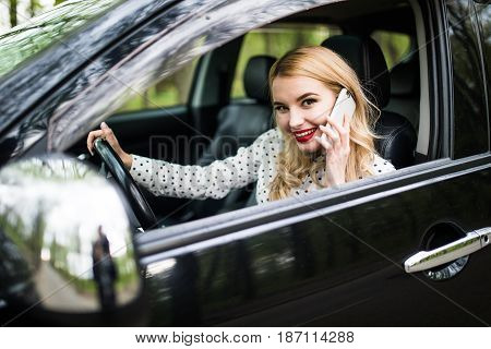 Young Woman With Telephone Having Phone Conversation While Driving Car On City Street