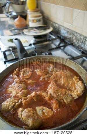 preparing ossobuco in pan with tomato sauce