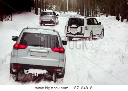 Three SUVs in the woods in winter in the rally. Driving SUV car in winter on forest road with much snow