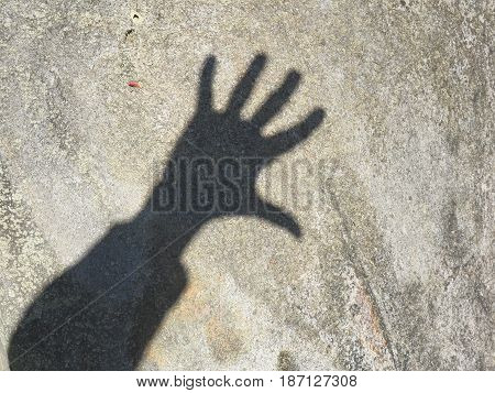 Hand shadow of the photographer on a grey stone on a Sunny day in the city Park
