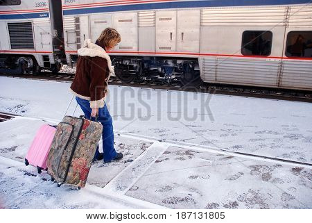KLAMATH FALLS, OREGON, USA - February 25, 2012: Passenger rolling her luggage towards an Amtrak train in snowy weather